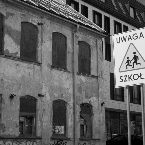 Czarno-białe budynki, przed nimi znak z napisem