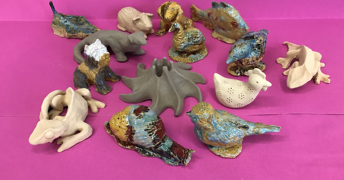 Różnorodne figurki ceramiczne na różowym tle.