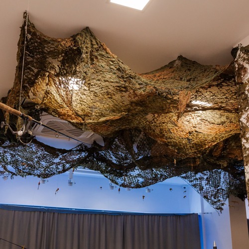 Z sufitu galerii zwisają rybackie sieci i przynęty, tworząc instalację o morskim charakterze.