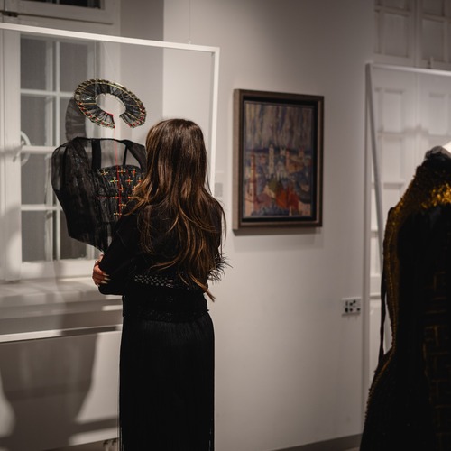 Kobieta ogląda czarną instalację artystyczną, zawieszoną na tle okna w galerii sztuki.
